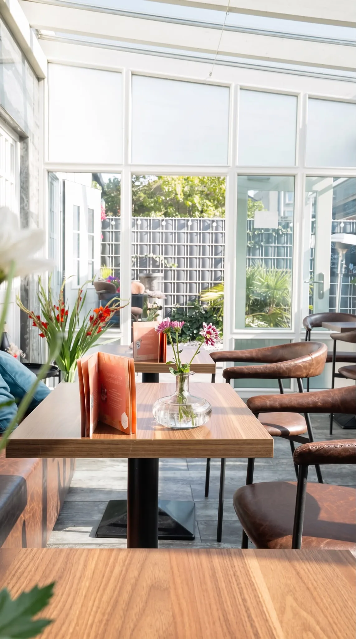 Der Wintergarten im FILOU mit Tischen und Blumen